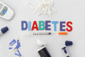 Word DIABETES with insulin syringe,lancet,test strip,glucose meter and lancing device on isolated white background