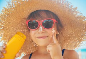 Little girl with hat sunglasses and sunscreen